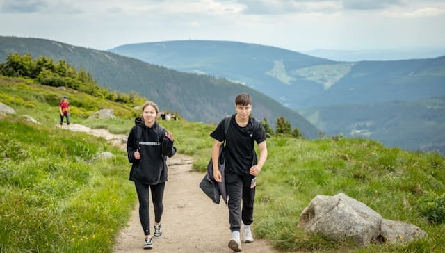 Dois estudantes caminhando em uma trilha nas montanhas com mochilas. Trilha em montanha durante intercâmbio